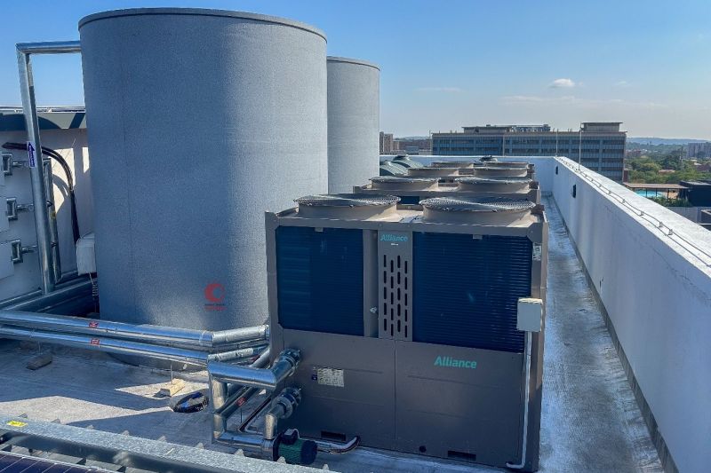 Rooftop HVAC area with large cylindrical storage tanks and a metal climate control unit with multiple pipes and vents.